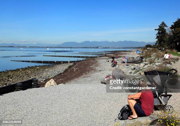 enjoying crescent beach with vancouver and north shore mountain background - white rock bc stock pictures, royalty-free photos & images