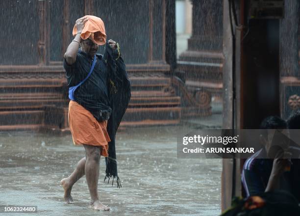 Indian Hindu devotee walks during heavy rains at Lord Ayyappa temple in Sabarimala in the southern state of Kerala on November 16, 2018. - Indian...