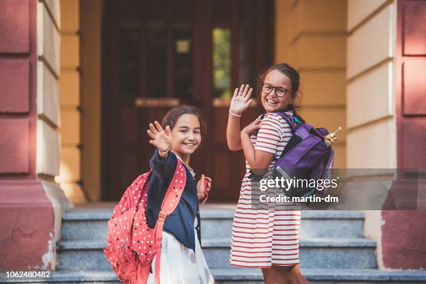 schoolkinderen zwaaien met hand aan hun ouders alvorens het schoolgebouw - waving stockfoto's en -beelden