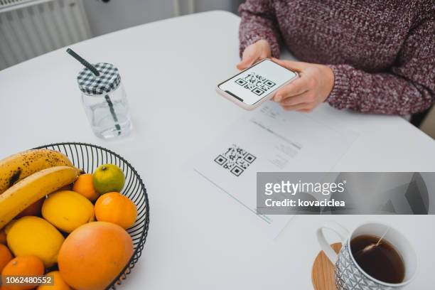 kvinna skanna qr-koden på en näbb med en smart telefon i köket - qr kod bildbanksfoton och bilder