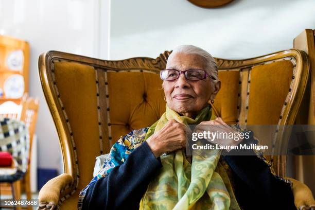 A woman putting on a scarf before leaving her home.