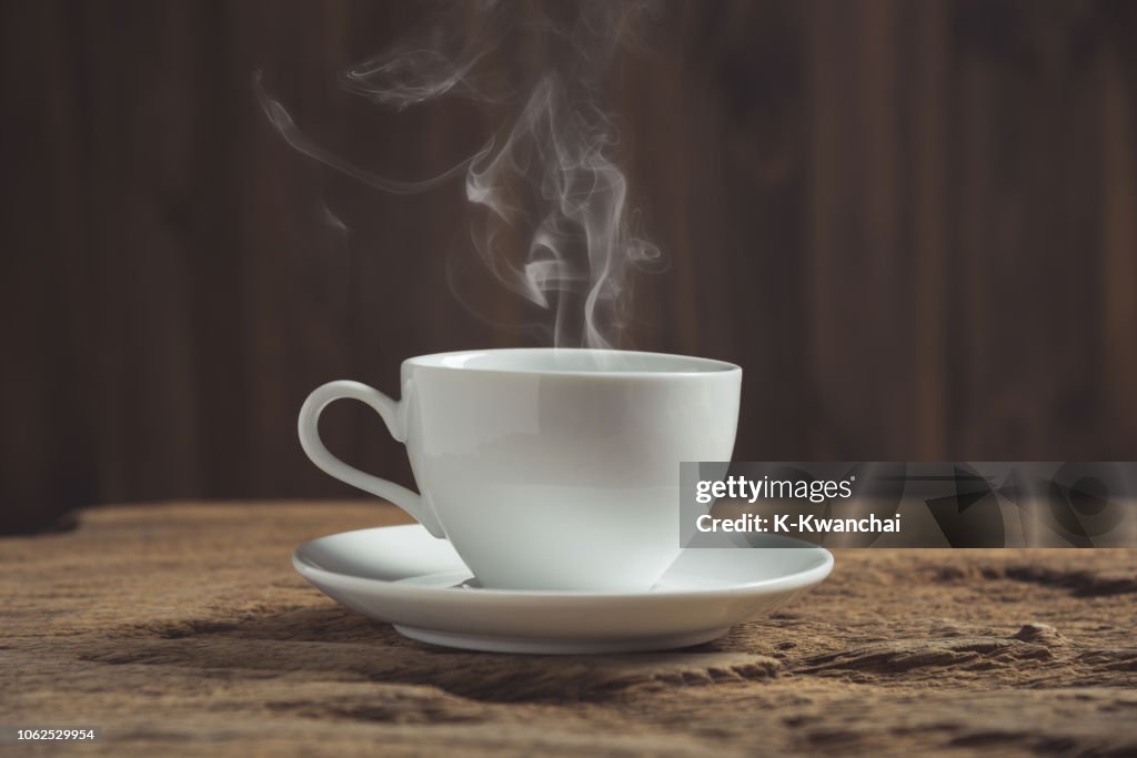 Nahaufnahme des Dampfes, der aus der Kaffeetasse auf dem Holztisch austritt