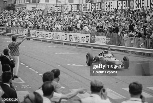 English racing driver Graham Hill drives the Owen Racing Organisation BRM P57 BRM P56 1.5 V8 racing car over the finish line to win the 1963 Monaco...