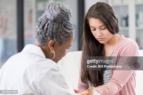 young woman shows hand injury to doctor - doctor reaching stock pictures, royalty-free photos & images