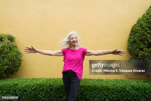 mature woman posing in a garden - hochgefühl stock-fotos und bilder