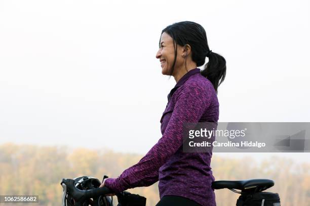 latina hispanic woman athlete riding a bicycle in park near lake - showus ストックフォトと画像