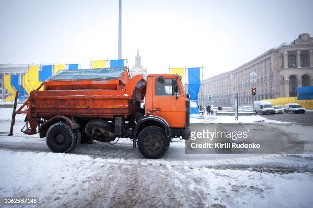 a communal truck spreading salt in a city during a heavy snowfall - road salt stock-fotos und bilder