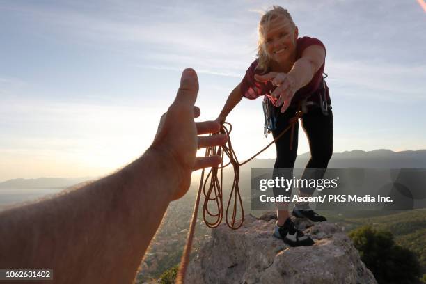 female rock climber extends a helping hand to teammate - berg klimmen team stockfoto's en -beelden