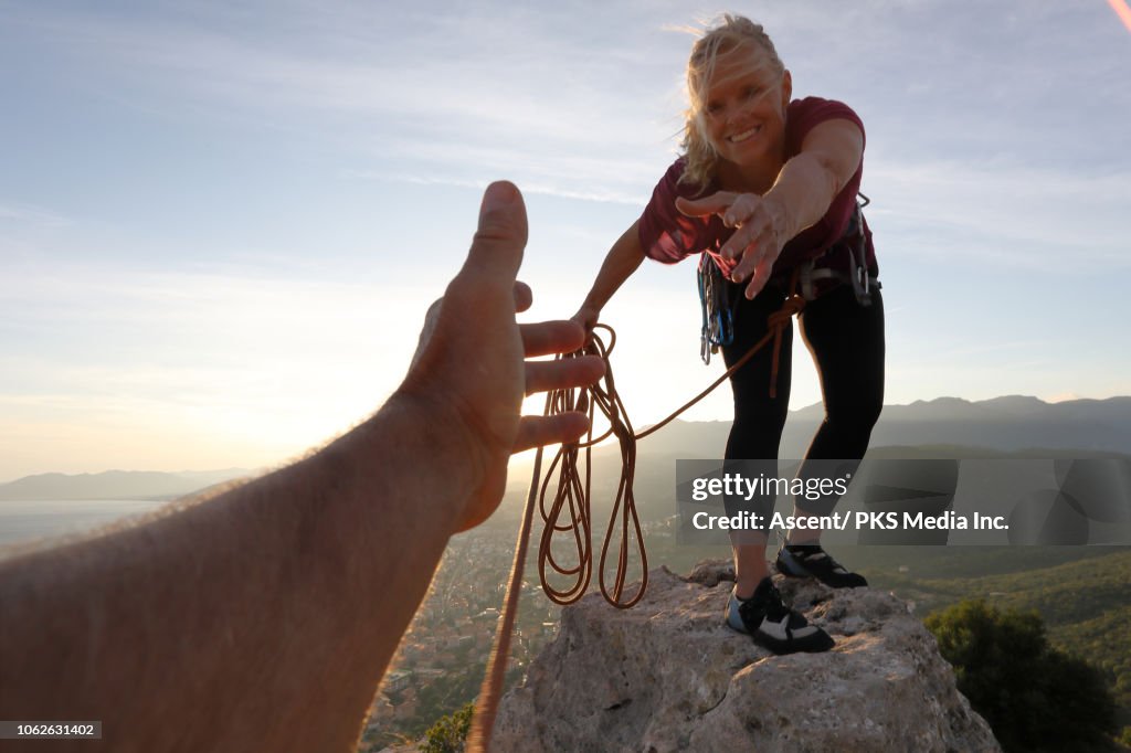 Female rock climber extends a helping hand to teammate