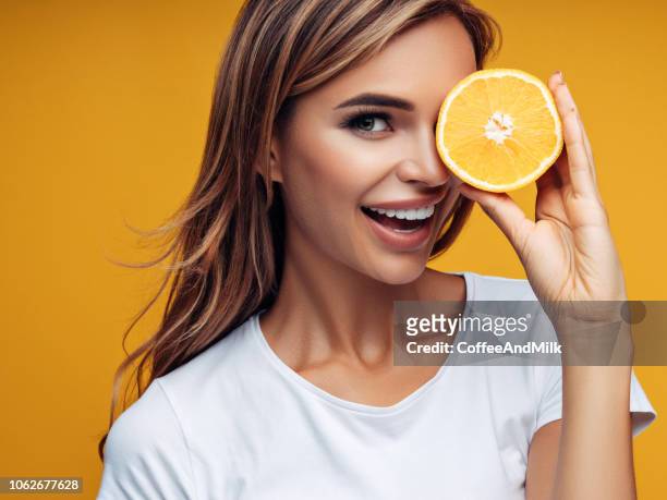 schöne mädchen zeigen zwei hälften einer zitrone - woman with orange stock-fotos und bilder