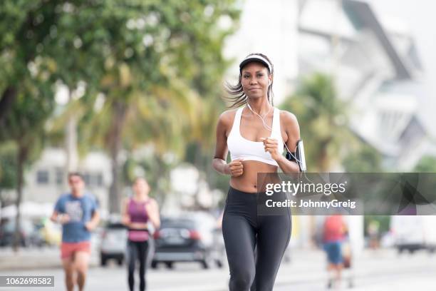 young woman jogging with headphones and pedometer on arm - praia de copacabana imagens e fotografias de stock