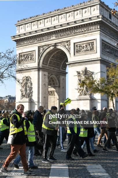 Demonstrators wearing Yellow Vests walk past the Arc de Triomphe in Paris on November 17, 2018 during a protest against the rising of the fuel and...