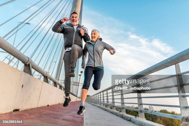 sportliche reifen brautpaar zusammen springen - old couple jumping stock-fotos und bilder