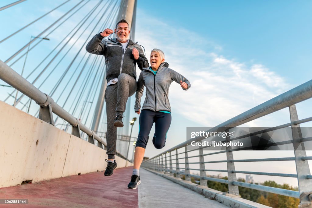 Happy athletic mature couple jumping together