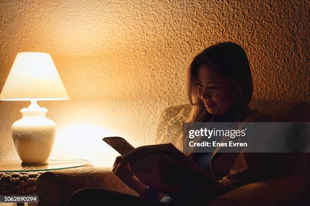 vrouw leesboek in de lobby van het hotel at night met weinig licht - low key stockfoto's en -beelden
