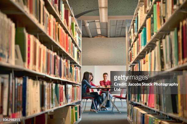 students studying at library table - bibliotheek stockfoto's en -beelden