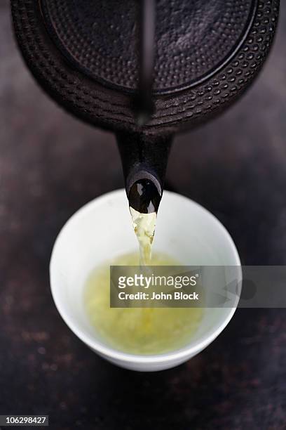 close up of japanese green tea being poured from teapot into cup - traditioneller brauch stock-fotos und bilder