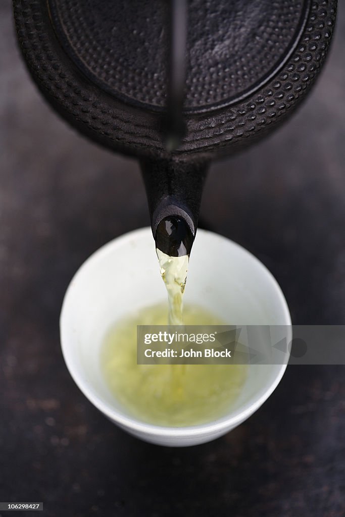 Close up of Japanese green tea being poured from teapot into cup