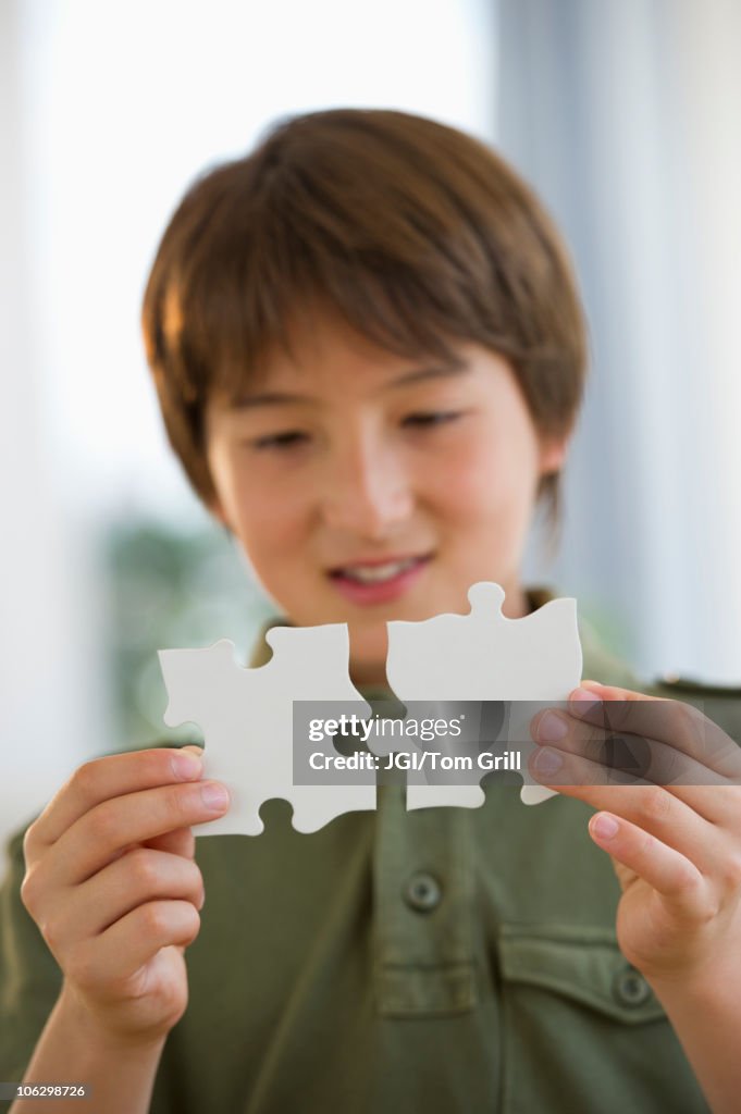 Mixed race boy connecting jigsaw pieces