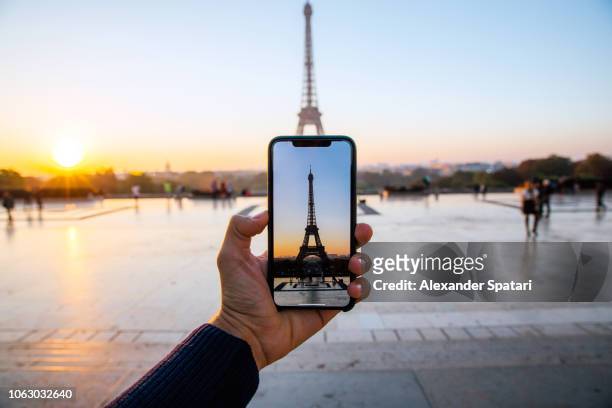 tourist taking picture of eiffel tower with smart phone, personal perspective view, paris, france - photo call stock-fotos und bilder
