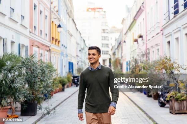 young happy smiling man walking on the street in paris, france - paris millenials stock-fotos und bilder