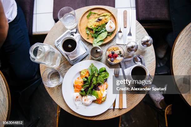 high angle view of brunch with avocado toast, salmon, poached egg and coffee on the table, served in cafe - food flatlay stock-fotos und bilder