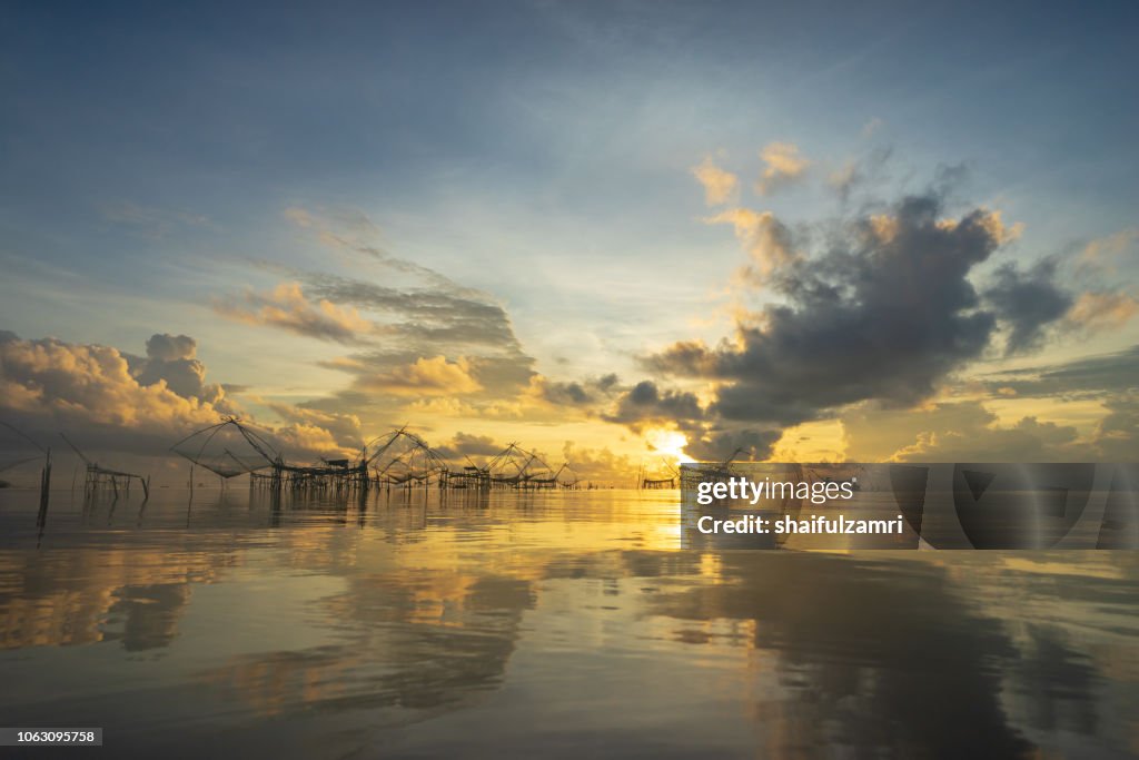 Traditional fishing nets made from bamboo and wood over golden sunrise at Phatthalung, Thailand.