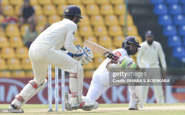 Sri Lanka's Niroshan Dickwella plays a shot as England's wicketkeeper Ben Foakes watch during the final day of the second Test match between Sri...