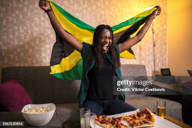 jamaican supporter watch sport on the tv - jamaica flag stock pictures, royalty-free photos & images
