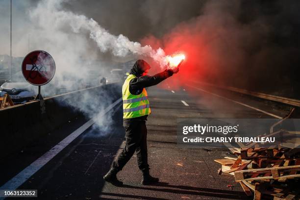 Man burn a flare as people block Caen's circular road on November 18, 2018 in Caen, Normandy, on a second day of action, a day after a nationwide...