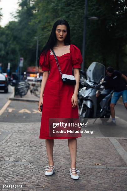 Model Wangy wears a red dress, black and white purse, and white flats during Milan Fashion Week Spring/Summer 2019 on September 22, 2018 in Milan,...