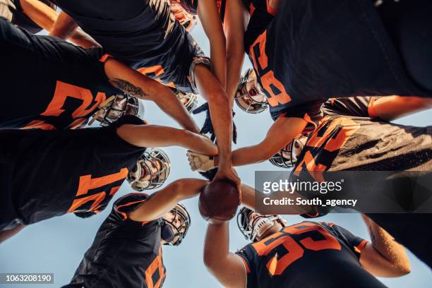 american football players huddling during time out - strategy game stock pictures, royalty-free photos & images