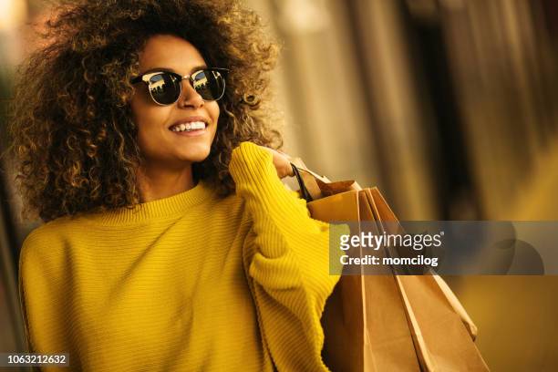 schöne mischungen rennen frau einkaufstaschen hält lächelnd - buying stock-fotos und bilder