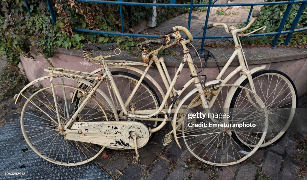 Two old parked and chained bycles.