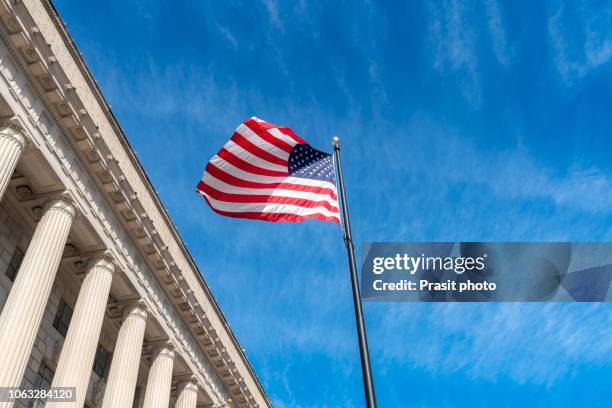 american flag flapping boldly in the wind with the supreme court in washington dc, usa. - us supreme court building stockfoto's en -beelden