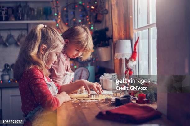 kleine mädchen bereiten weihnachts-cookies mit cookie-cutter - baked goods stock-fotos und bilder