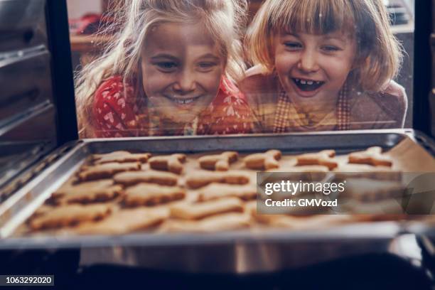 little girls waiting for christmas cookies to bake in the oven - emotions stock pictures, royalty-free photos & images