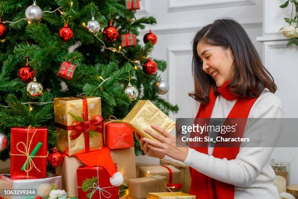 jeune femme asiatique assise sur le sol et pack emballage de cadeaux en face de l’arbre de noël sur le salon, les vacances de noël et les cadeaux concept jour de boxe - asian six pack photos et images de collection