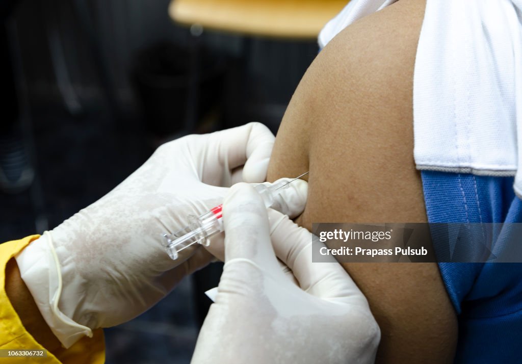 Doctor giving patient vaccine, flu or influenza shot or taking blood test with needle. Nurse with injection or syringe. Medicine, insulin or vaccination. Hospital office room.