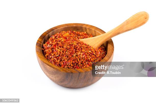 crushed red chili pepper in wooden bowl on white background - chilli powder stock-fotos und bilder
