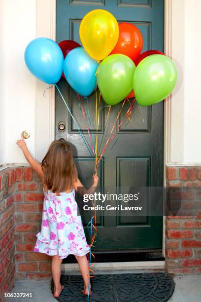 girl holding balloons ringing a doorbell - girl doorbell stock pictures, royalty-free photos & images