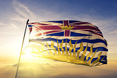 British Columbia province of Canada flag textile cloth fabric waving on the top sunrise mist fog