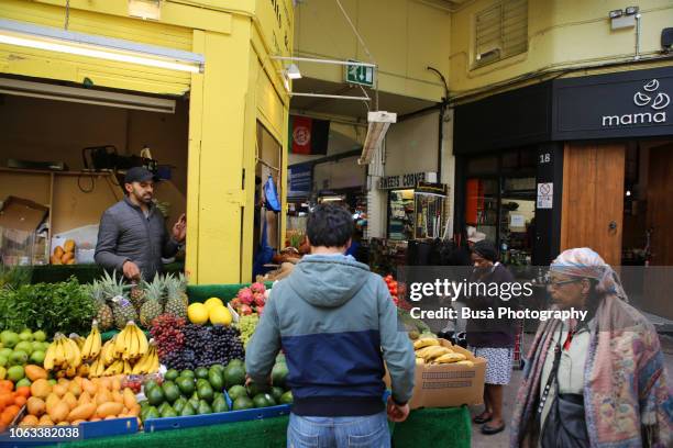 fruit and vegetable vendor inside brixton village market, a shopping arcade in brixton, london, uk - brixton stock pictures, royalty-free photos & images