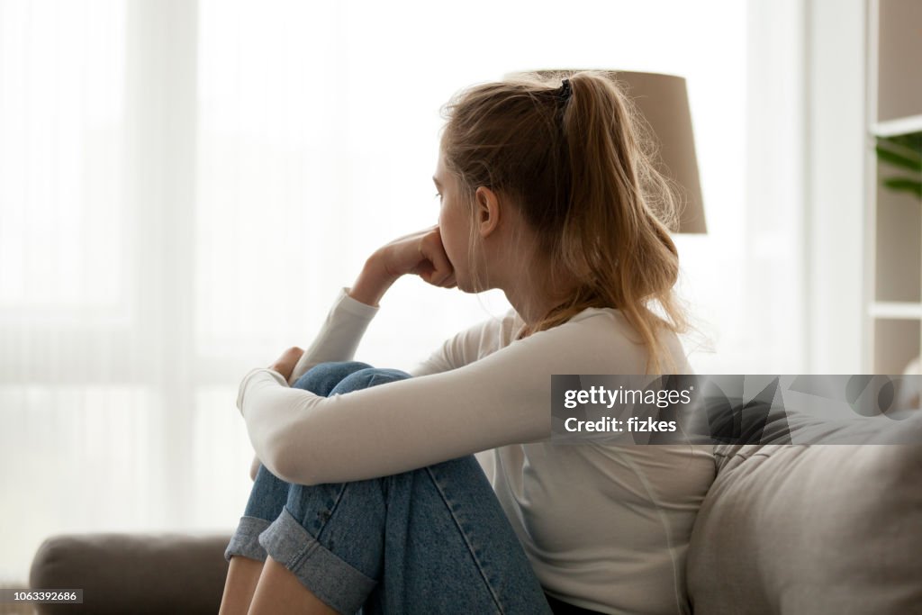 Upset woman sitting on couch alone at home