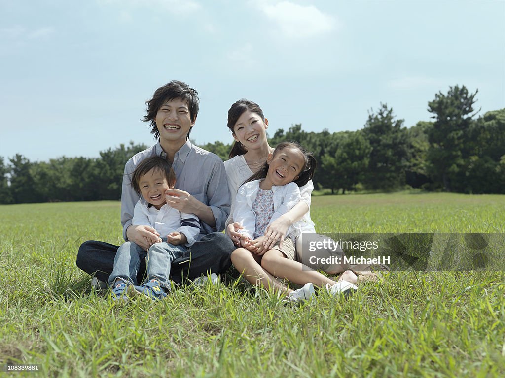 Family who sits on lawn in park
