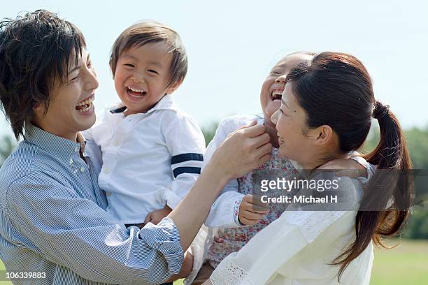 family who happily with a smile in park - family smile photos et images de collection