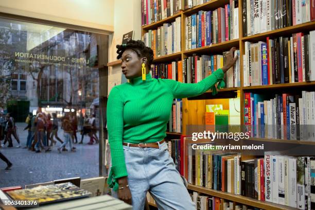 young black woman in a library - libreria fotografías e imágenes de stock