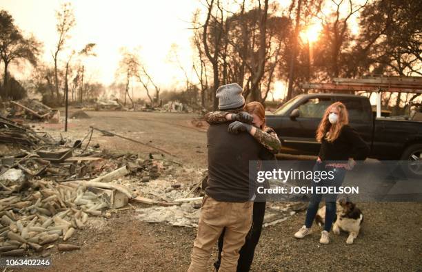 Kimberly Spainhower hugs her husband Ryan Spainhower while their daughter Chloe Spainhower looks on at the burned remains of their home in Paradise,...