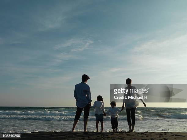 family who sees sea in beach in evening - four people holding hands stock pictures, royalty-free photos & images