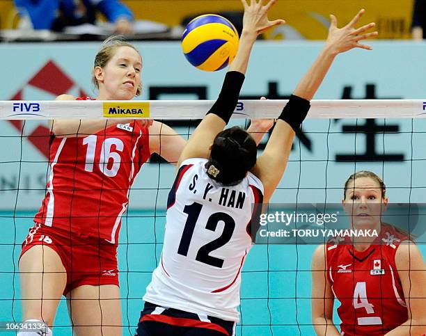 Jennifer Hinze of Canada spikes the ball over Han Song-Yi of South Korea as Canadian captain Tammy Louise Mahon looks on during their first round...